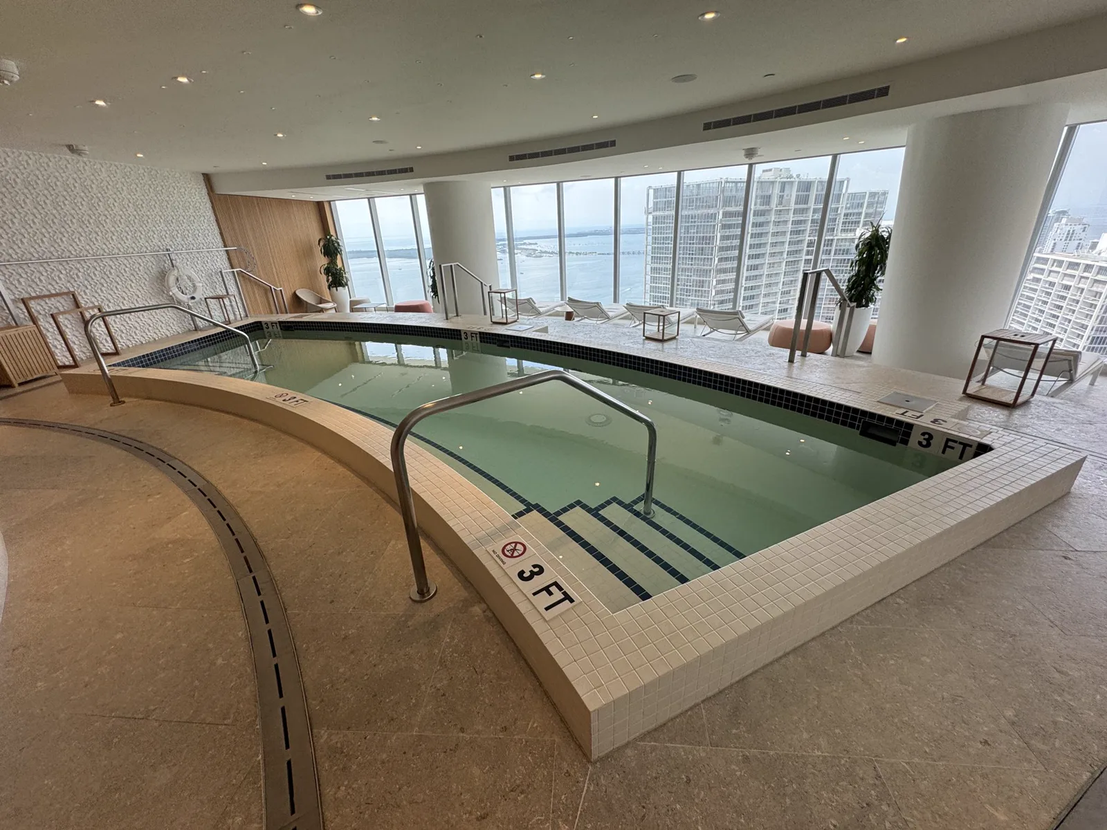 Indoor swimming pool with curved edge and city views at Aston Martin Residences