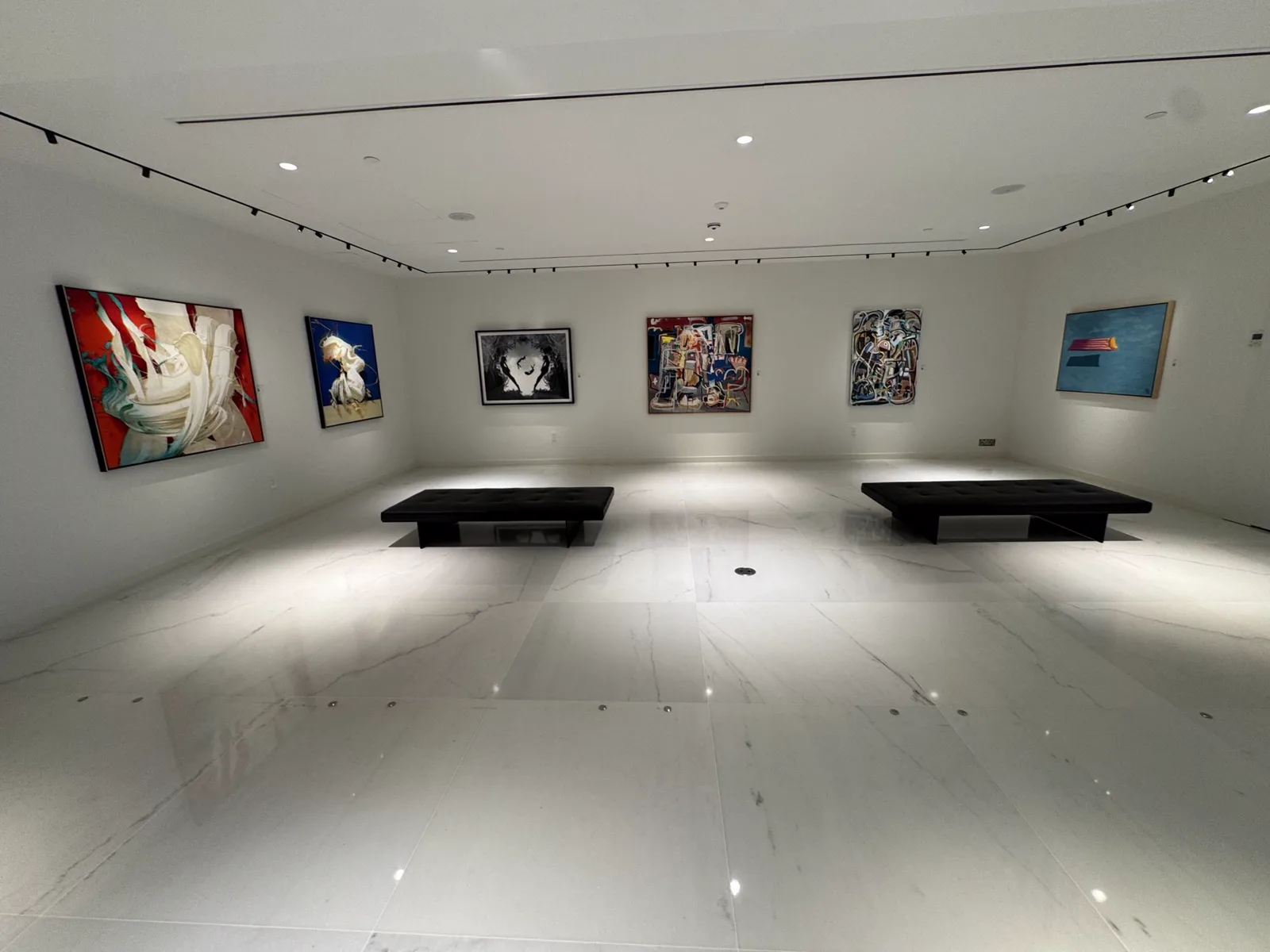Bright art gallery common area with framed paintings and stone flooring