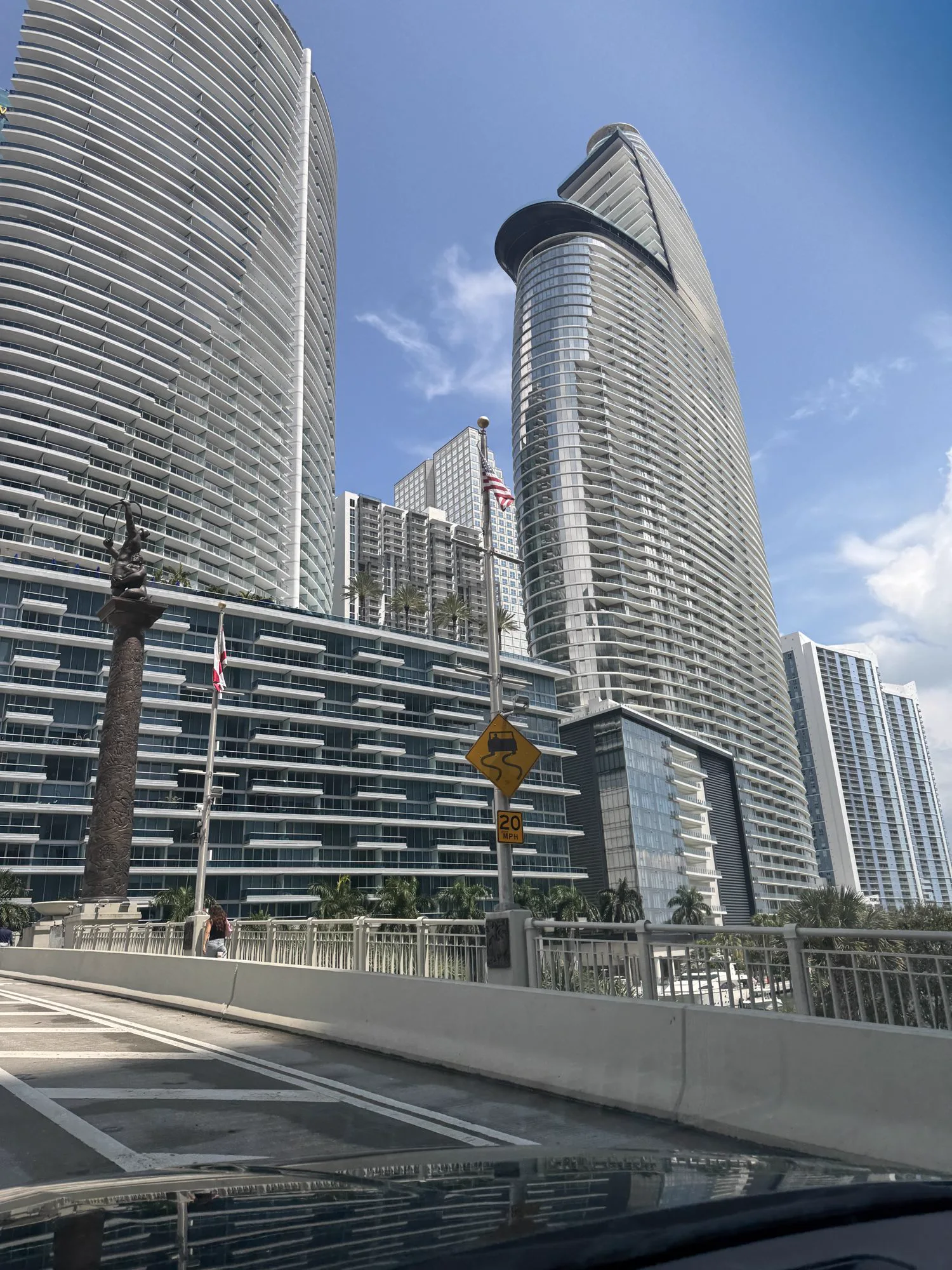 Curved glass towers of Aston Martin Residences seen beside a downtown Miami bridge
